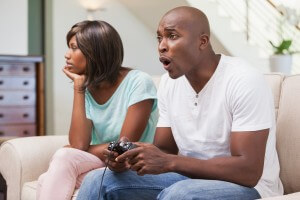 Bored woman sitting next to her boyfriend playing video games at